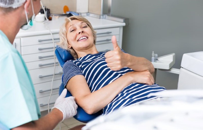 Dental patient in treatment chair, giving thumbs up 