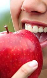 Closeup of patient with dental implants in Studio City eating an apple