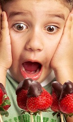 Child gaping at a row of chocolate-covered strawberries