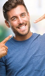 young man pointing to his smile with straight white teeth 