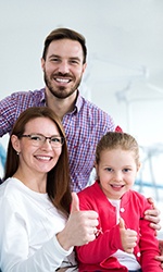 Adults and their child with dentist in treatment chair