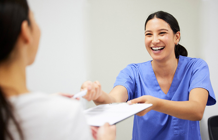 staff member handing insurance forms to patient 