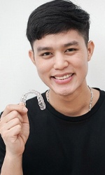 A young man holding an Invisalign aligner