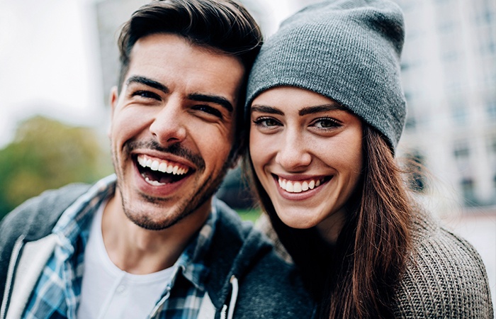 Young man and woman smiling outdoors