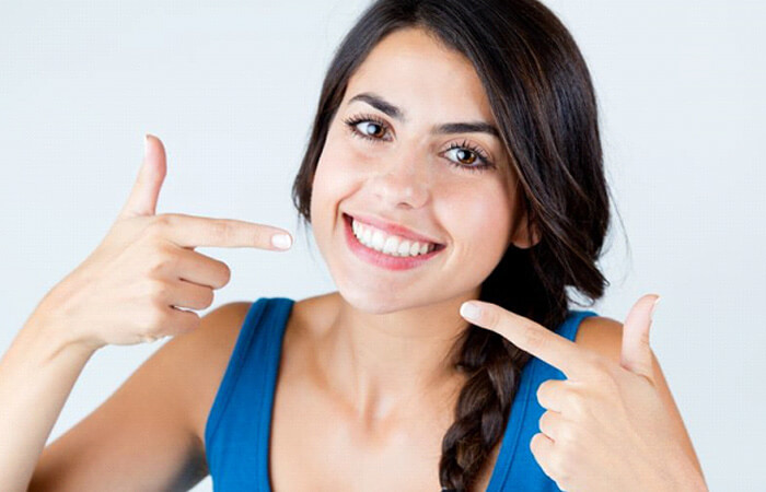 attractive woman pointing at her beautiful teeth and gums