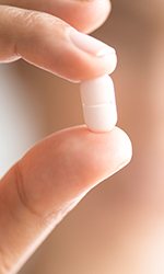 Hand holding white tablet pill
