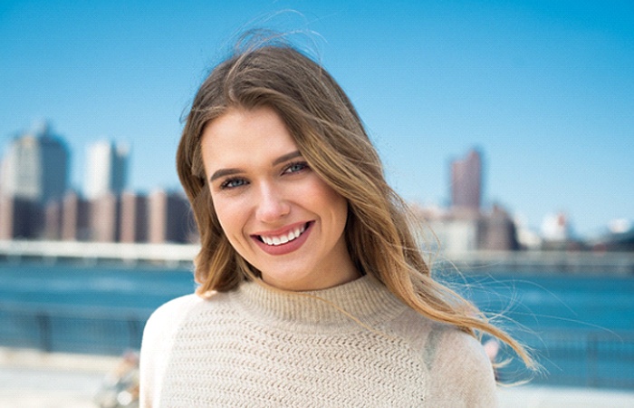 Woman smiling next to ocean and city skyline