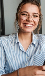 Woman with glasses smiling while holding her phone