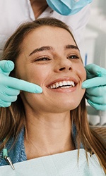 Smiling patient with white teeth looking at reflection in mirror