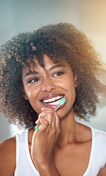 Woman with white teeth smiling while brushing teeth