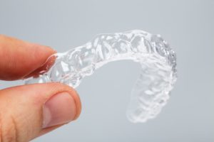 A person holding a clear aligner tray.