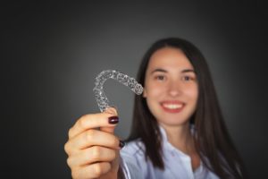 Woman holding clear aligner for Invisalign.