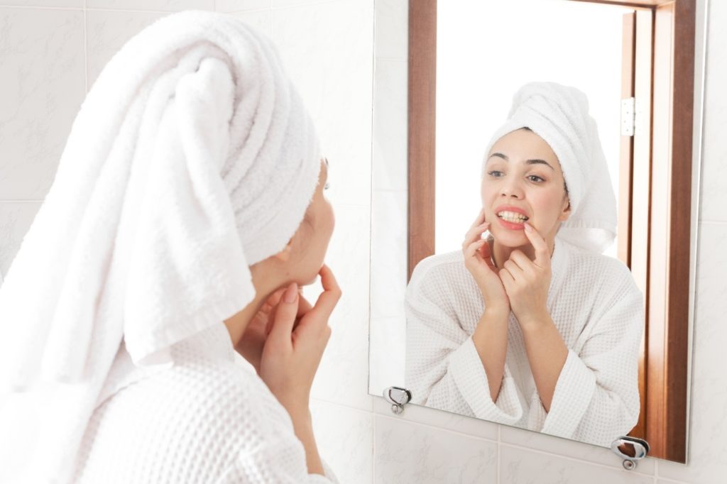 Woman looking at her teeth and gums in the mirror