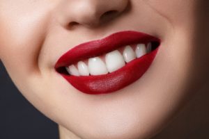 a person smiling and wearing red lipstick 