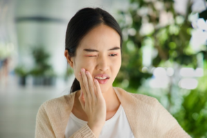 Woman wincing and rubbing one side of her jaw